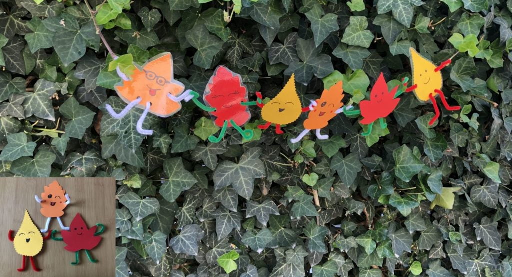 színes kartonpapírból készült levél-pajtik összekapaszkodva egy borostyánnal futatott kerítésen