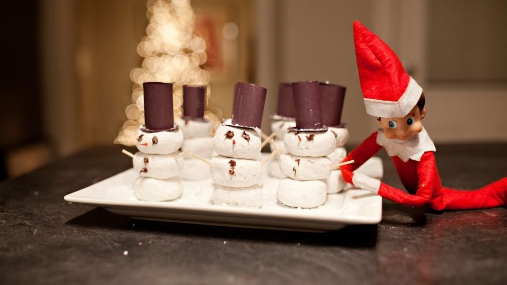 karácsonyi manó pillecukorból hóembereket készít egy tálra